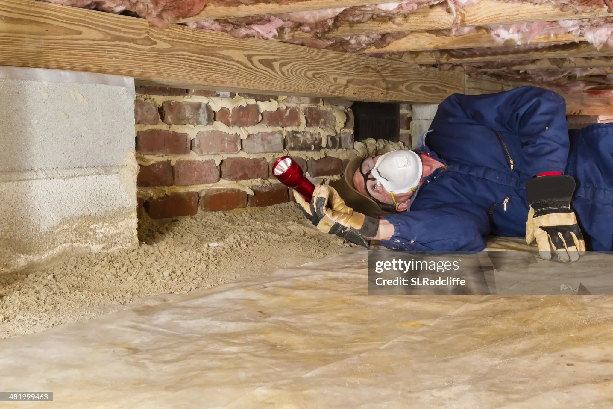 A specialist inspecting potential water in a crawl space.