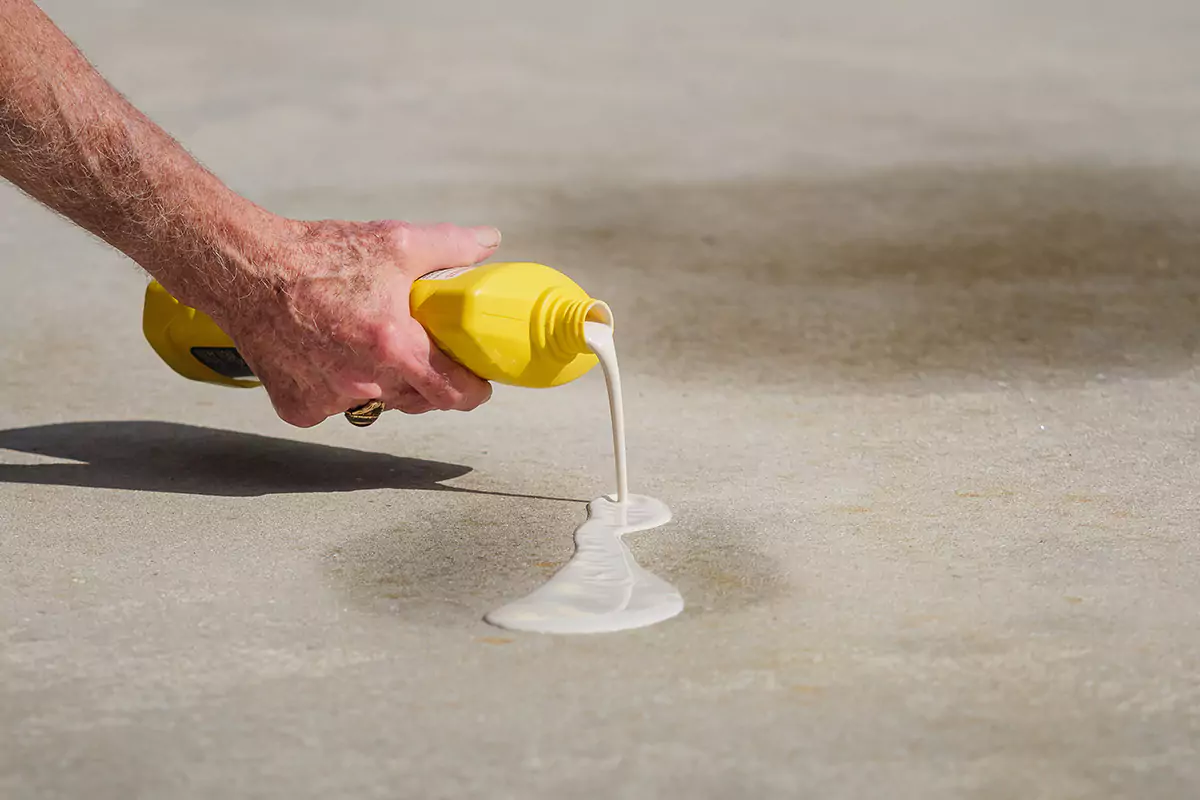 A person using a solvent to clean concrete.